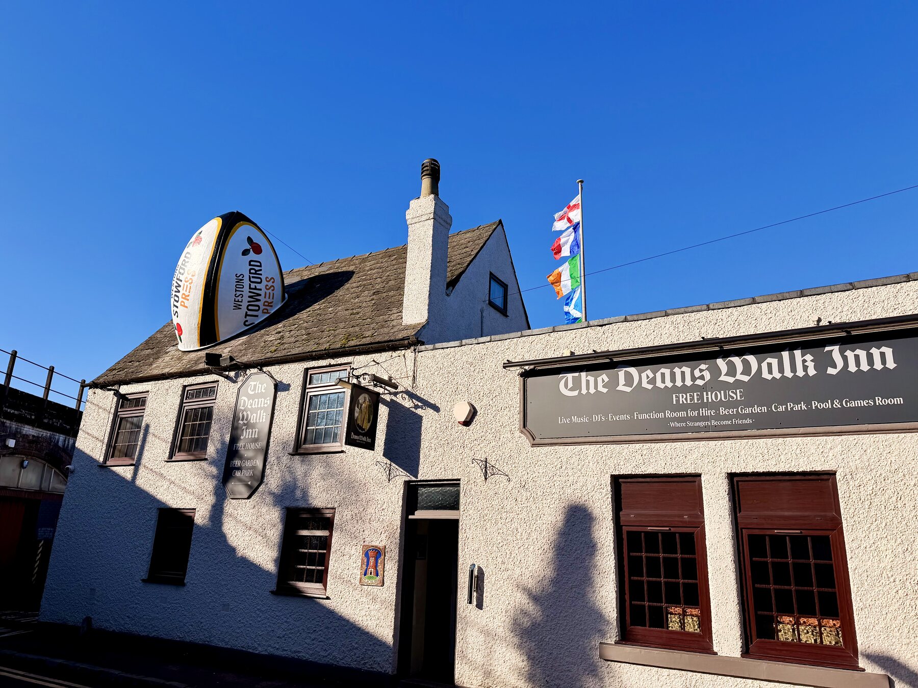 Deans Walk Inn on a sunny day, with the pub sign and flags